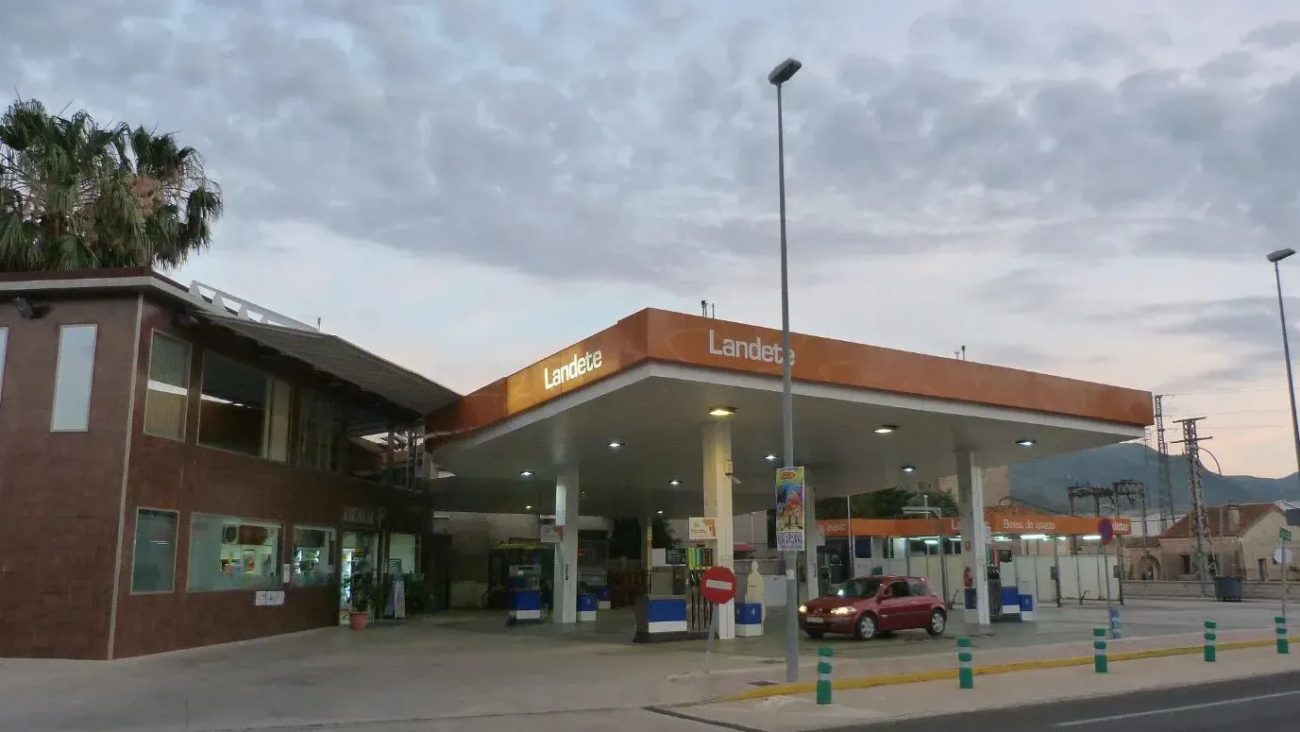 773626 - Gasolinera Landete | CR Diario Gas station with orange canopy reading Landete, pumps under a covered forecourt and a red car at a pump under a cloudy sky.