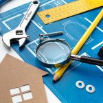 782293 - Kibac Disseny | CR Diario Architectural blueprint with a pencil, magnifying glass, wrench, and measuring tools on a desk