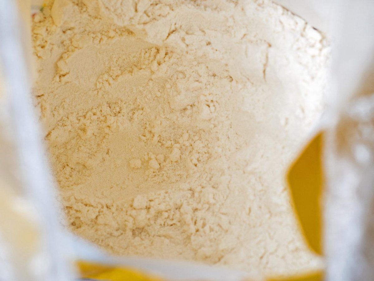 Close-up top view of a bag of white wholemeal flour | CR Diario Bag of pale flour, close-up inside a plastic package on a kitchen counter.